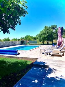 una piscina con sillas y una sombrilla junto a una piscina en Holiday Home Endi, en Unešić