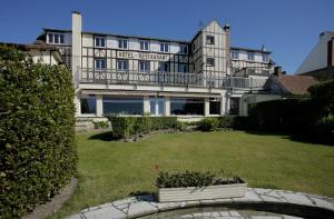 ein großes weißes Gebäude mit einem Balkon in einem Hof in der Unterkunft Le Normandy in Wissant