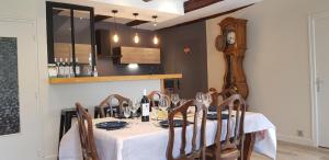 uma sala de jantar com uma mesa com cadeiras e um relógio em Lodge-Sagne une ferme rénovée au cœur du Cantal à proximité de la station de ski du Lioran 