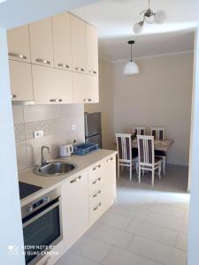 una cocina con armarios blancos y una mesa con sillas. en Apartmani Popović V&A, en Tivat