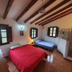 1 dormitorio con cama roja y sofá azul en Casa del rio, en Málaga