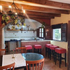 cocina con mesa y taburetes rojos en Casa del rio, en Málaga