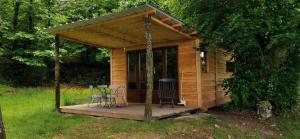 a small wooden cabin with a table and chairs at camping de la chagnée in Saint-Aubin-le-Cloud