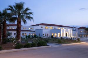 a large white building with palm trees and a street at Eretria Hotel & Spa Resort in Eretria