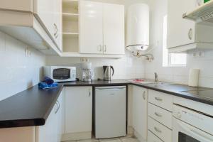 een witte keuken met witte kasten en een magnetron bij Apartment Sleepy Hollow in Carvoeiro