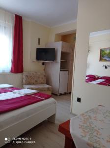a hotel room with two beds and a television at Akác Vendégház in Eger
