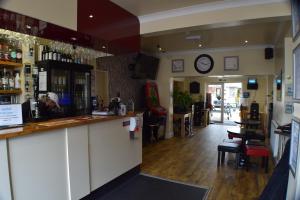 eine Bar in einem Restaurant mit einer Uhr an der Wand in der Unterkunft Seashells Beach Hotel in Sutton on Sea