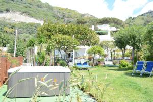 a garden with blue chairs and a house at Hotel Maronti in Ischia