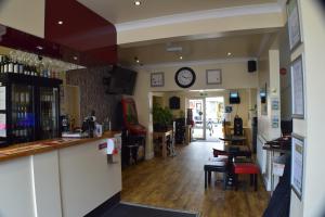 a bar with chairs and a clock on the wall at Seashells Beach Hotel in Sutton on Sea