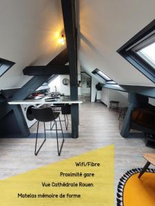 a loft with a table and chairs in a room at Lodge de la Gare Vue Cathédrale in Rouen