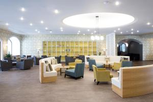 una sala de espera con sofás, mesas y sillas en Eretria Hotel & Spa Resort, en Eretria