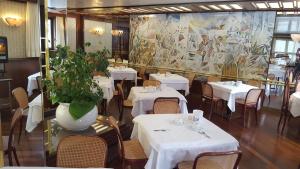 a restaurant with white tables and a large painting on the wall at Hotel Cristallo in Madonna di Campiglio