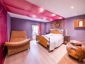 a bedroom with purple walls and a bed and a chair at Zen inspired Holiday Home in Orchimont with Jacuzzi in Orchimont