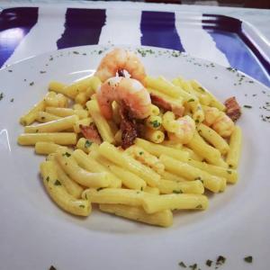 a plate of pasta with shrimp and sauce on a table at Hotel Flora in Cesenatico