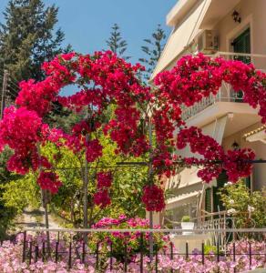 a fence with pink flowers in front of a building at Vicky's Guesthouse in Kavos