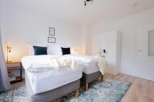 1 dormitorio con 1 cama con sábanas blancas y alfombra azul en cruwzo I Apartment Rüttenscheid- Grün & Zentral, en Essen