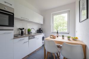 cocina con mesa de madera y electrodomésticos blancos en cruwzo I Apartment Rüttenscheid- Grün & Zentral, en Essen