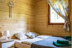 Cama en habitación de madera con ventana en Dusznickie Domki Całoroczne, en Duszniki-Zdrój