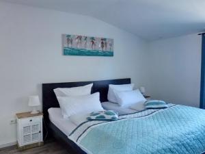 a bed with a blue blanket and pillows on it at Haus am Burggraben in Hinte