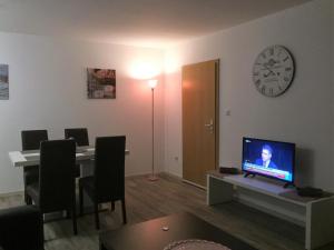 a living room with a desk with a television and a clock at Haus am Burggraben in Hinte