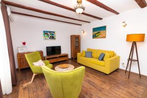 sala de estar con 2 sofás amarillos y TV en Villa Melita, en Opatija
