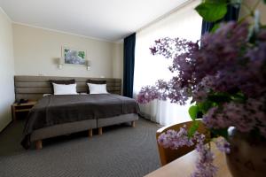 ein Schlafzimmer mit einem Bett und einem Fenster mit lila Blumen in der Unterkunft Spa Hotel Ezeri in Sigulda