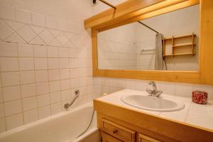 a bathroom with a sink and a tub and a mirror at Residence La TROIKA 2 in Notre-Dame-de-Bellecombe