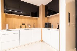 una cocina con armarios blancos y electrodomésticos negros en Studio Silesian Vip City Centrum Free Parking en Zabrze