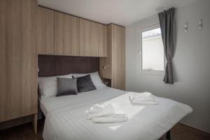 a bedroom with a large white bed with towels on it at Terra Park Phalaris in Novalja