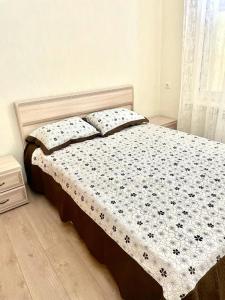 a bedroom with a bed with a floral bedspread and pillows at Guest House Aleksina in Lazarevskoye