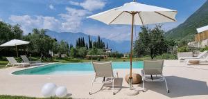 a pool with two chairs and an umbrella and a table and chairs at Elle Ecoholiday in Malcesine