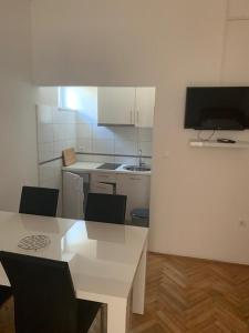 a white kitchen with a white table and chairs at Apartmani MM in Starigrad-Paklenica