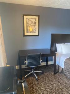 einen Schreibtisch in einem Hotelzimmer mit einem Bett und einem Stuhl in der Unterkunft Fairview Inn - Greensboro Airport in Greensboro