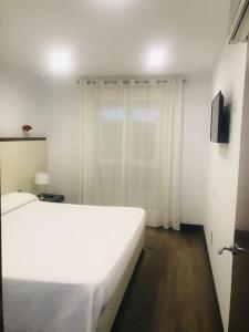um quarto com uma cama branca e uma janela em Apartamento 5 EN PRIMERA LÍNEA DE PLAYA CON VISTAS AL MAR em Almeria