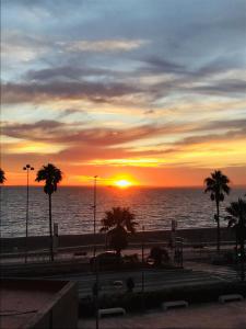 um pôr do sol na praia com palmeiras e o oceano em Apartamento 5 EN PRIMERA LÍNEA DE PLAYA CON VISTAS AL MAR em Almeria