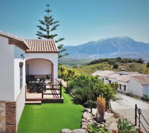 uma casa com um quintal verde com montanhas ao fundo em Alojamientos Huetor em Viñuela