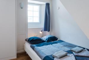 Schlafzimmer mit einem Bett mit blauer Bettwäsche und einem Fenster in der Unterkunft HITrental Schmidgasse - Apartments in Zürich