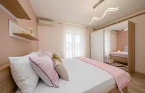 a bedroom with a bed with pink and white pillows at Apartments Luka in Rab