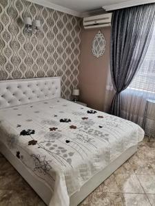 a bedroom with a white bed with flowers on it at Guest House Konomaevi in Sozopol