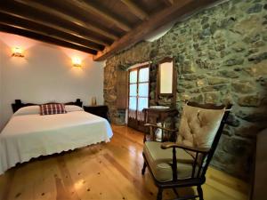 a bedroom with a bed and a stone wall at La Casina de Orfeo Cuenco Cangas de Onís VV-1901-A in Cangas de Onís