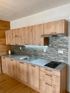 a kitchen with wooden cabinets and a sink at Apartment Ďumbier in Mýto pod Ďumbierom