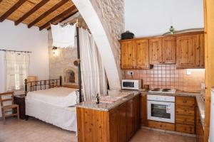 a kitchen with a bed in a room with wooden cabinets at Andros traditions house in Kathikas