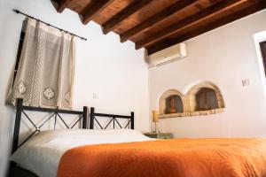 1 dormitorio con 1 cama con colcha de color naranja en Andros traditions house, en Káthikas