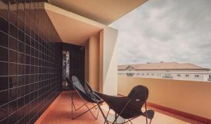 a balcony with two chairs and a building at Ceuta Terrace Suites in Porto