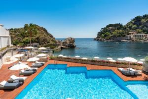 a swimming pool with chairs and a view of the ocean at Mazzarò Sea Palace - The Leading Hotels of the World in Taormina