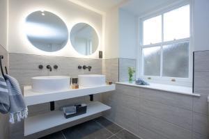 two sinks in a bathroom with two mirrors at Golden Vanity, Maritime Suites, Brixham in Brixham