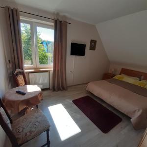 1 dormitorio con cama, ventana y silla en Agroturystyka Brzozowe Wzgórze en Wleń