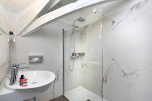 ein weißes Bad mit einer Dusche und einem Waschbecken in der Unterkunft Le Manoir Les Minimes in Amboise