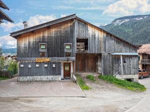 an old wooden barn with a door and mountains at Ciasa Lino Aloch in Pozza di Fassa