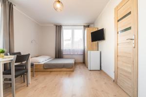 a small room with a bed and a desk and a table at Pokoje Gościnne Lipowa in Sztutowo